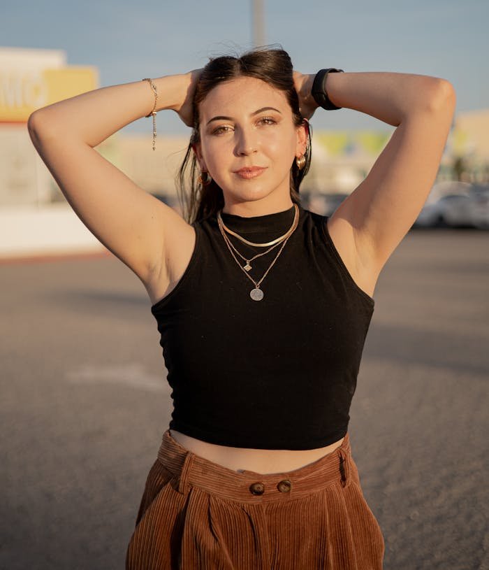 A woman in a black top and brown pants poses for a photo
